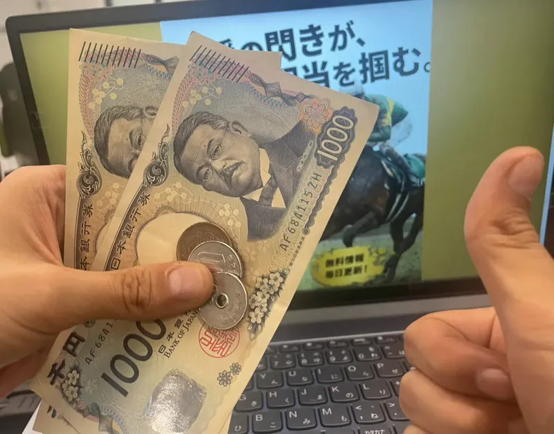 うまトリの検証画面の前で、無料予想の最初の的中払戻金（2,160円）を手にしている様子